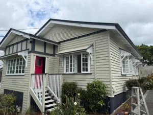 Exterior house painting completed on a Queenslander in beige and charcoal with a red front door